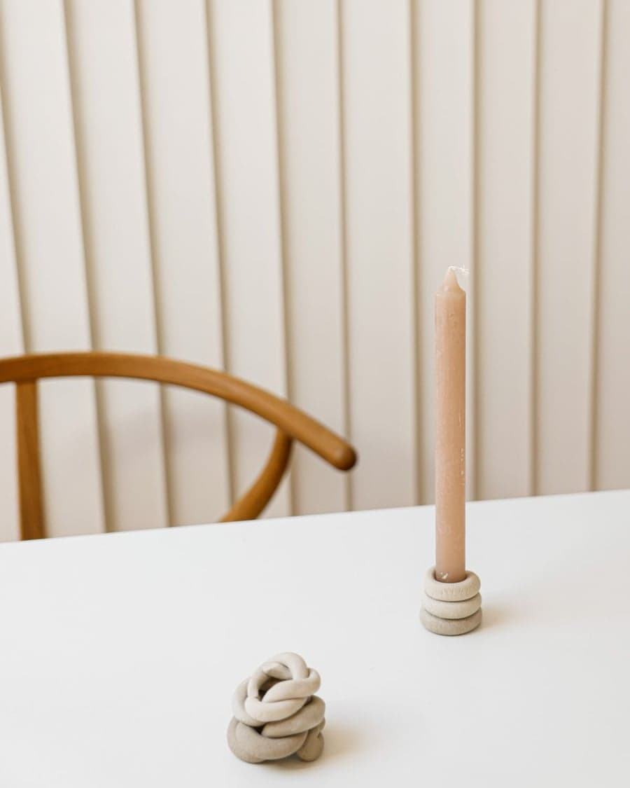 Beige Kerze in einem schlichten Halter auf hellem Tisch