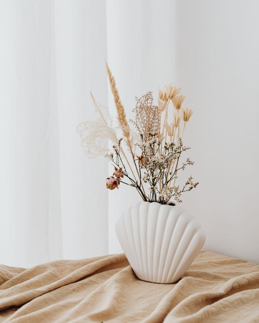 Muschelförmige weiße Vase mit Trockenblumen